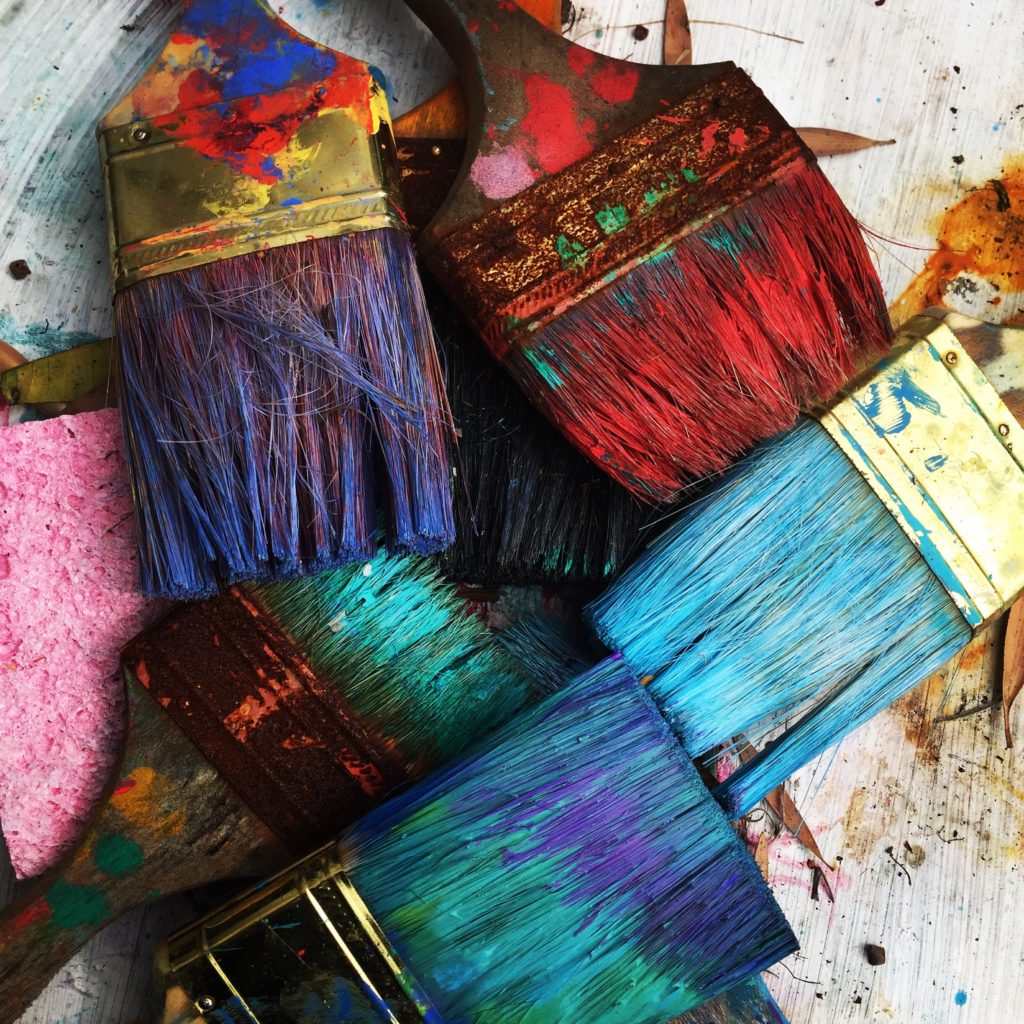 several paintbrushes stained with different brightly colored paints