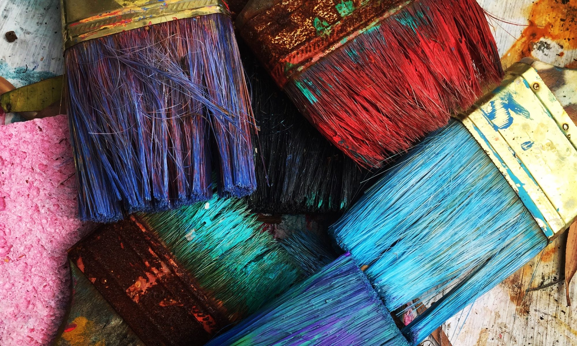 several paintbrushes dipped in different brightly colored paint