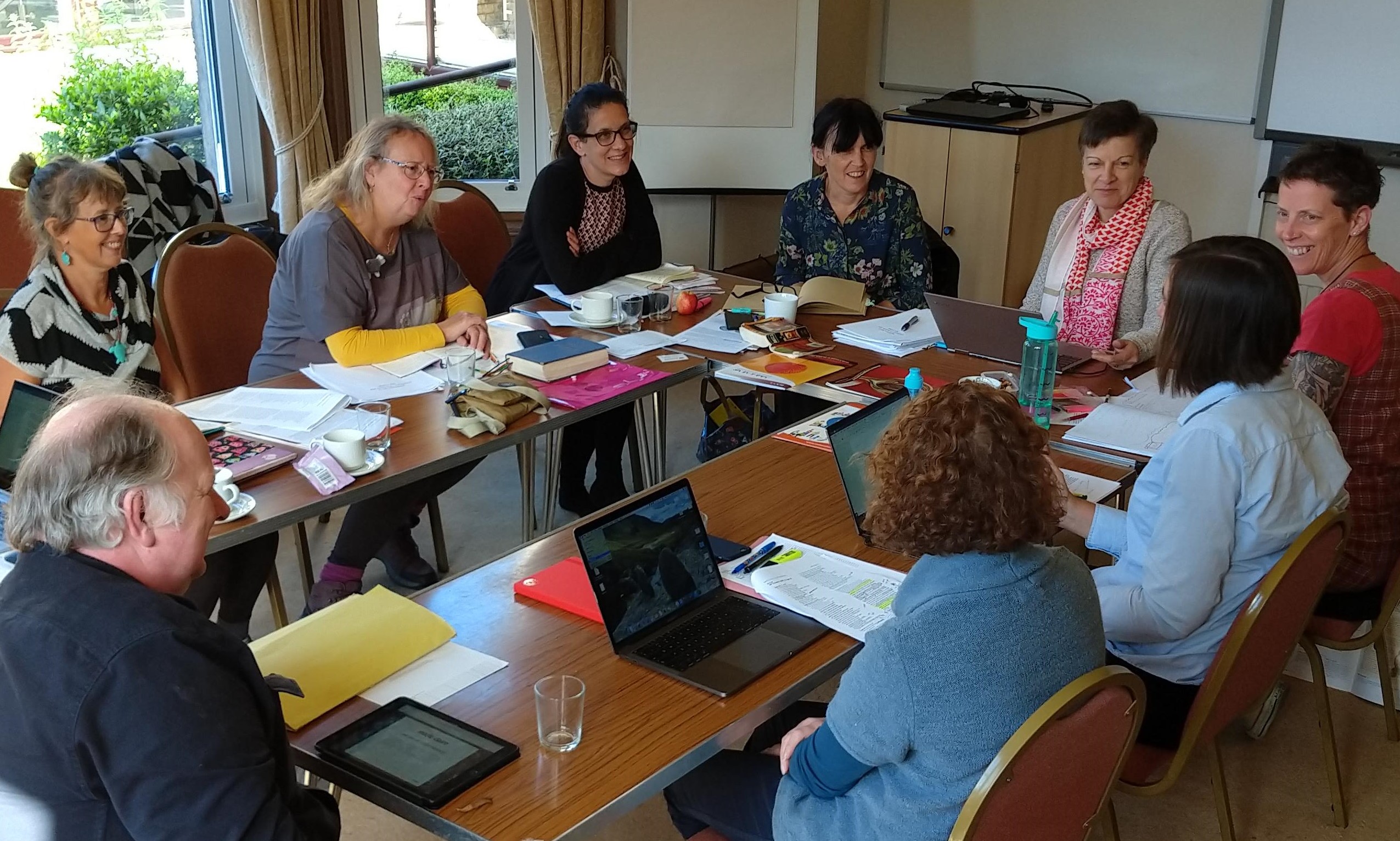 Photograph of a ROOTS writers conference showing adults around a table smiling and talking