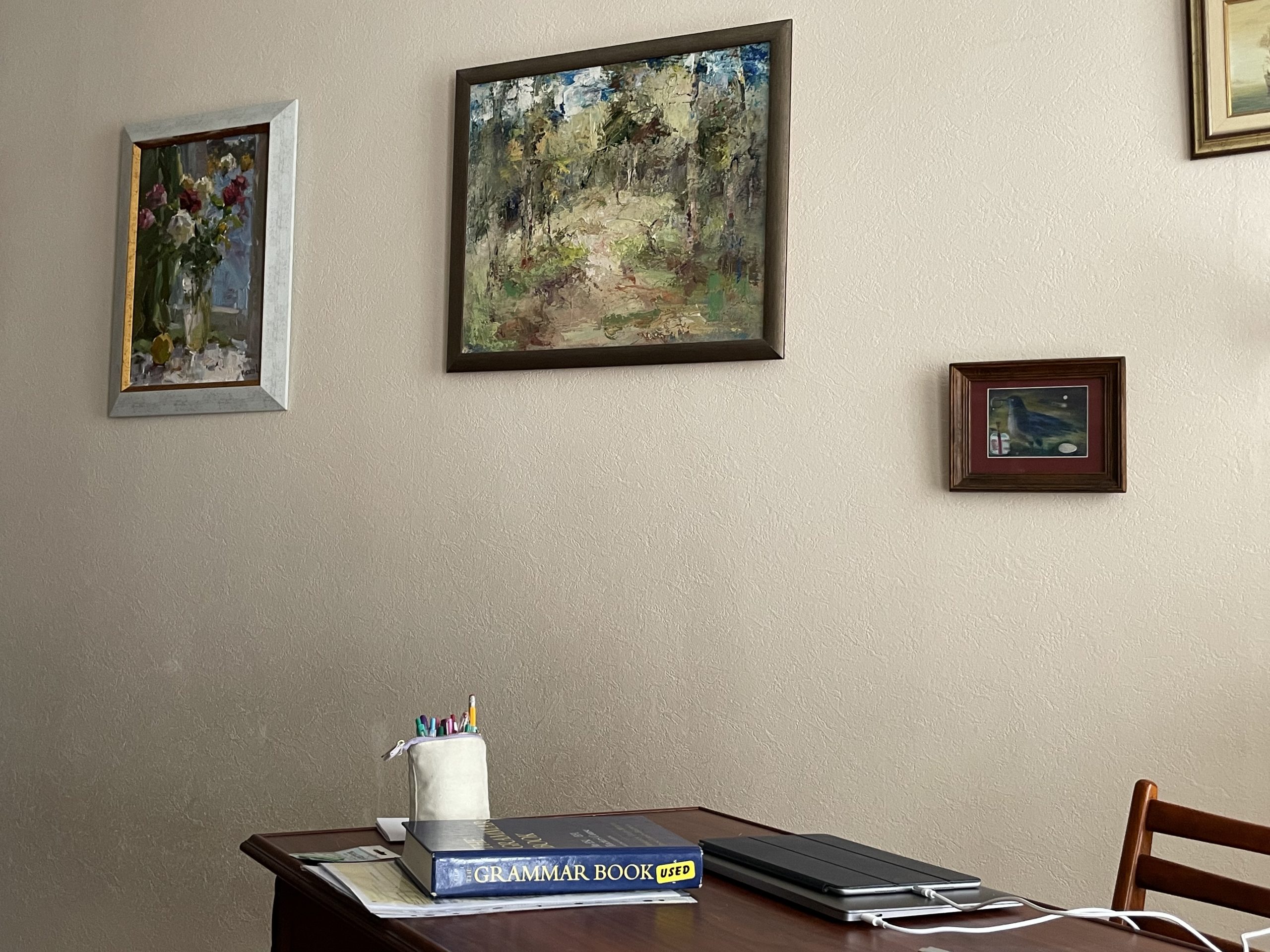 Framed art hangs on a beige wall above a writing desk.