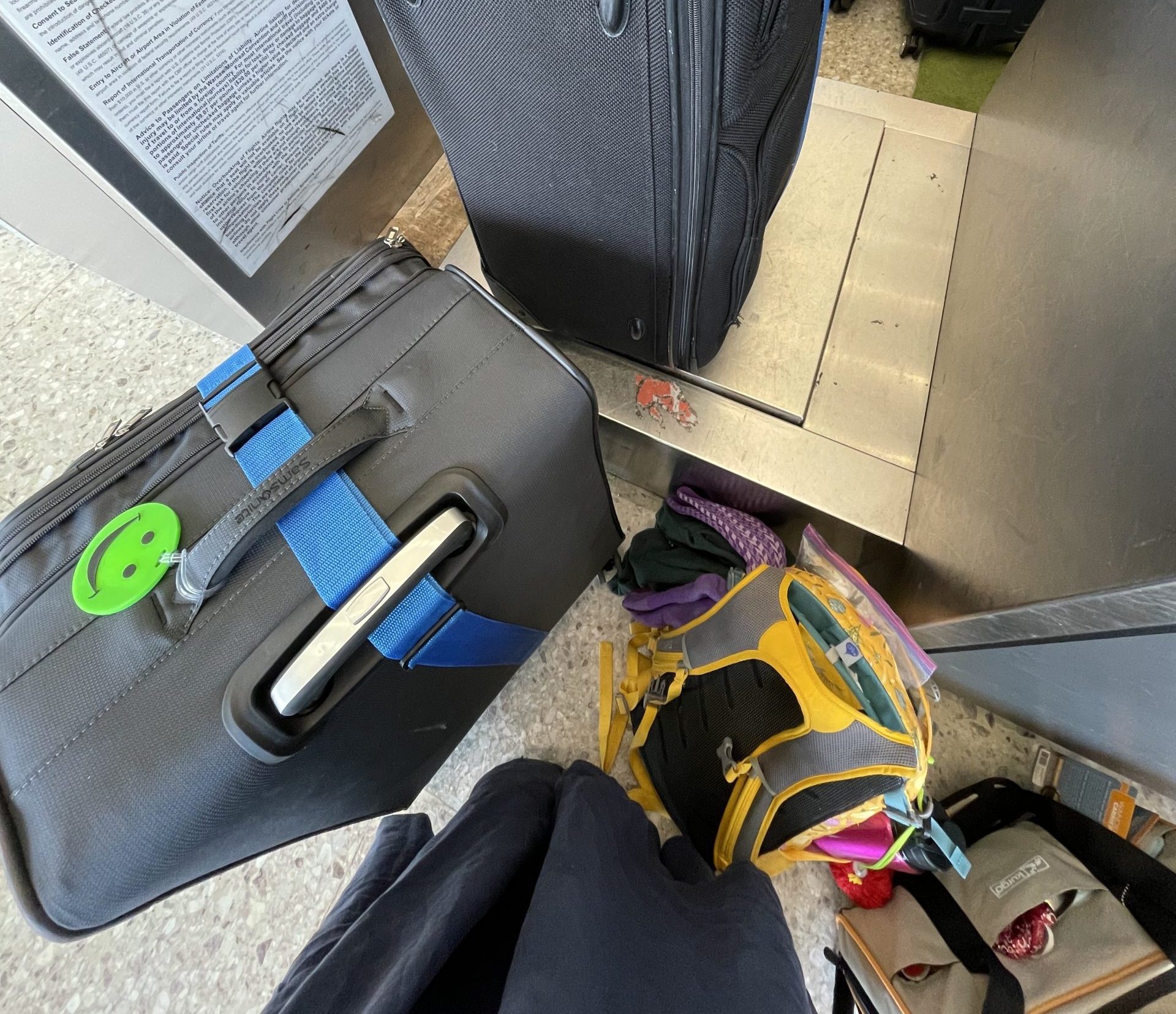 Looking down from the photgrapher's perspective, seen clockwise from lower right: cat carrier, backpack, photographer's skirt, suitcase, suitcase, suitcase, suitcase. At the airport, turning over the suitcases at the ticketing counter.