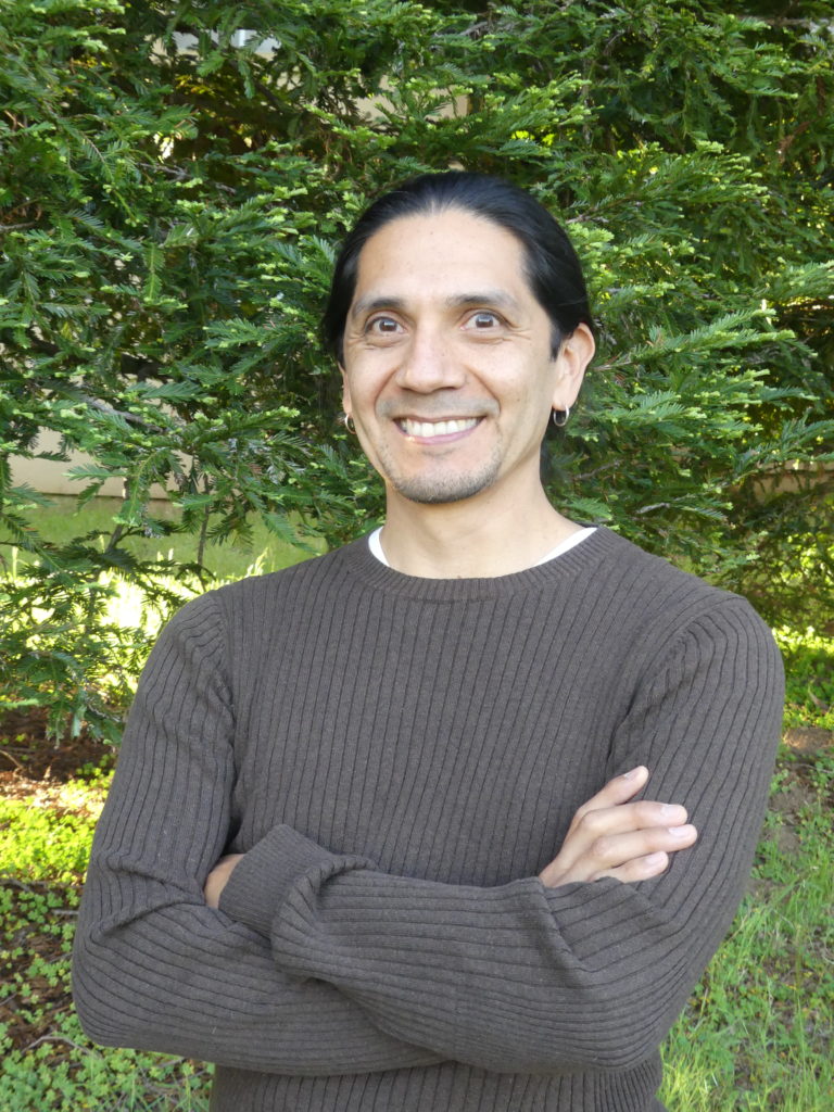 STEM Ed PaCER Fellow Dr. Salvador Huitzilopochtli. Black hair either short or tied back, small hoop earrings, big smile, gray sweater.